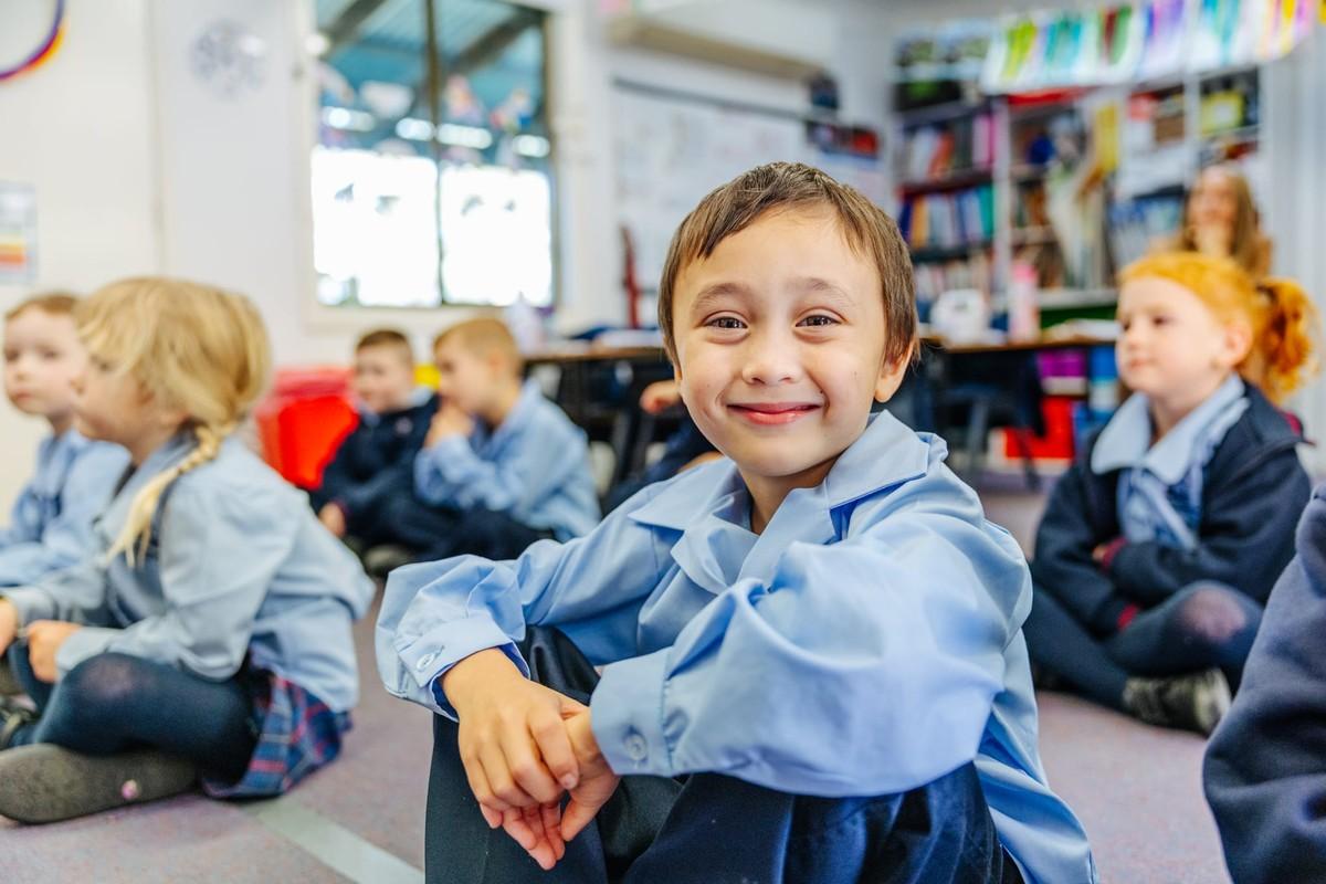 Smiling primary student sitting with classmates — discover primary school at Brightwaters CC.