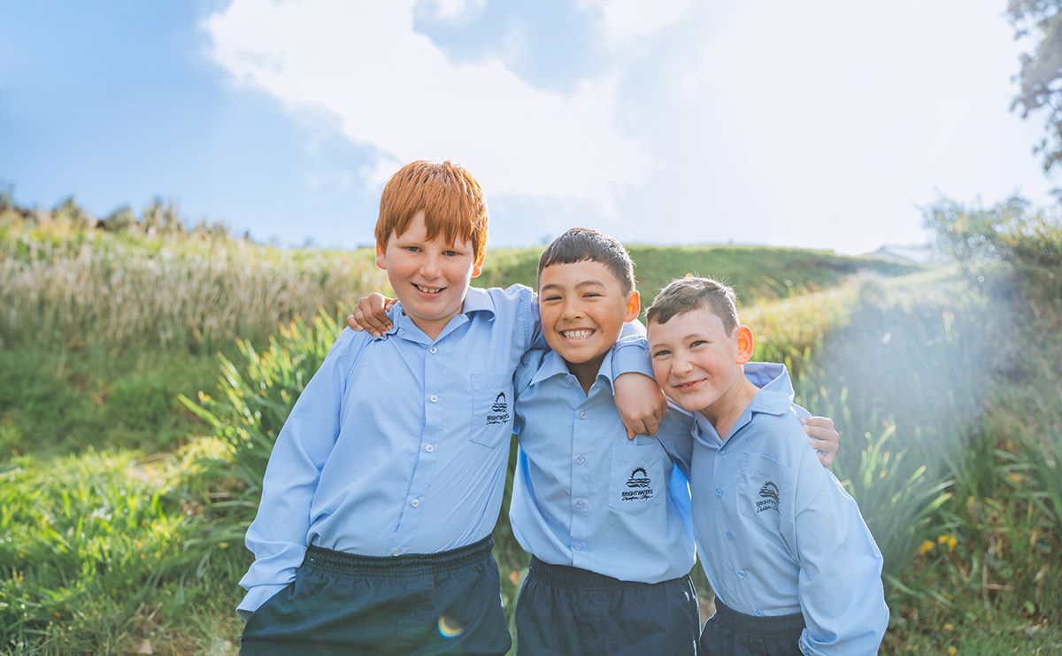 Three smiling male student friends in uniform who have built a strong relationship