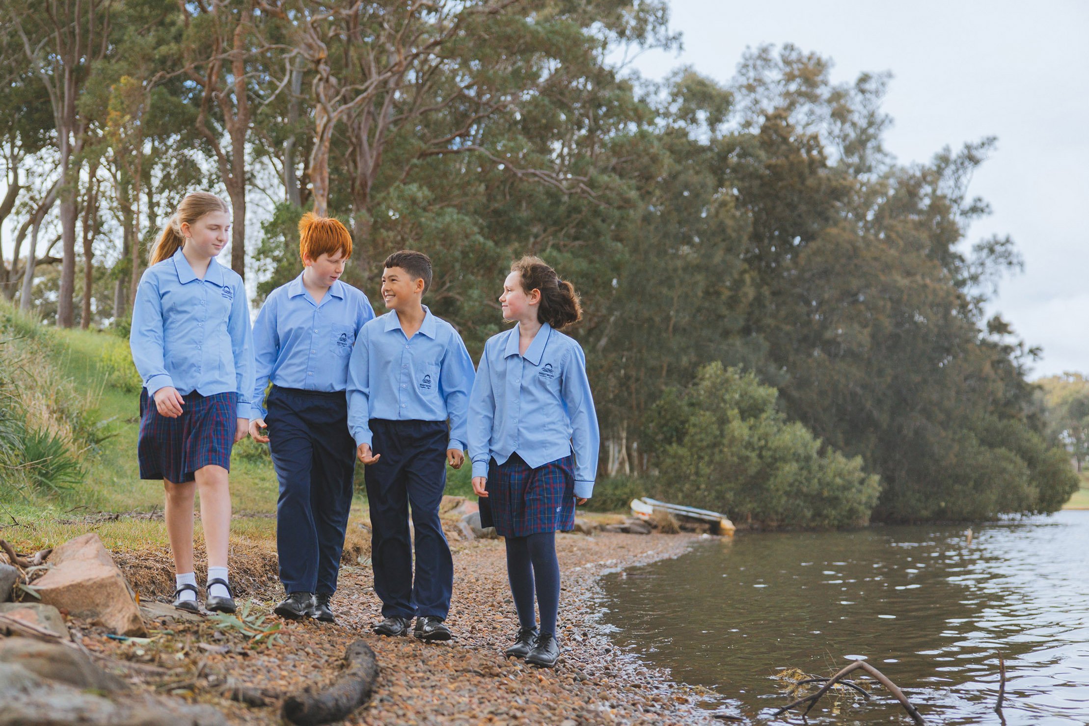Group of happy students walking together in nature on school campus